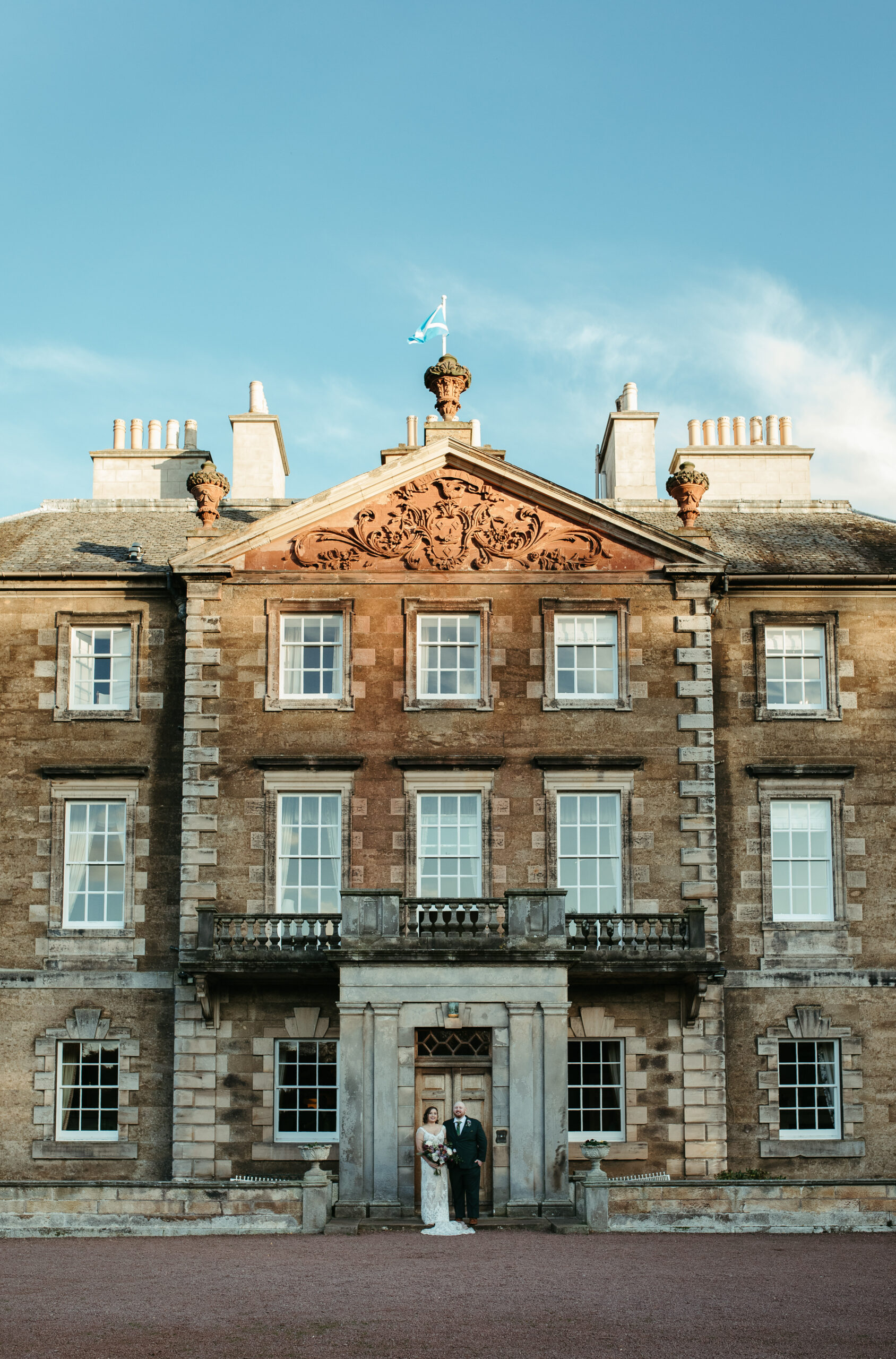 Alex and Charlie Scotland wedding. Couple standing in front of Gilmerton House. Photography by Charlotte Kinsella