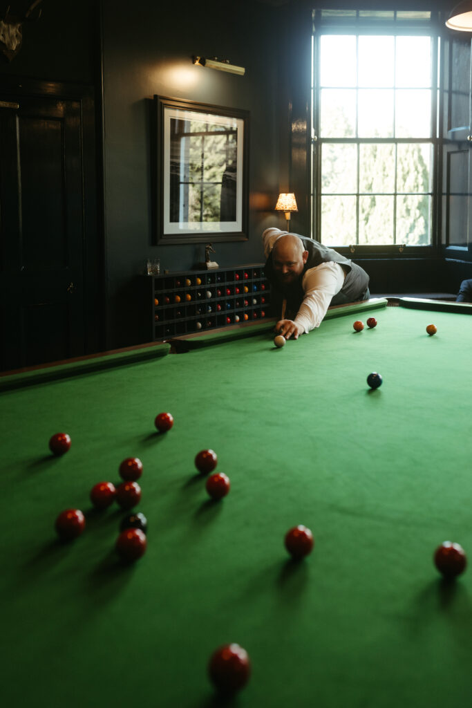Groom, Charlie, playing pool at Gilmerton House to prepare for the big day