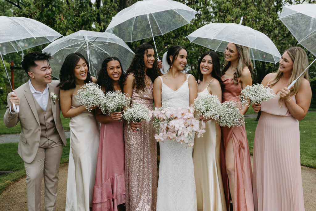 bridal party standing under umbrellas taking photos at their wedding in the California rain planned by Talia Eliana Events/Terra Coast Events