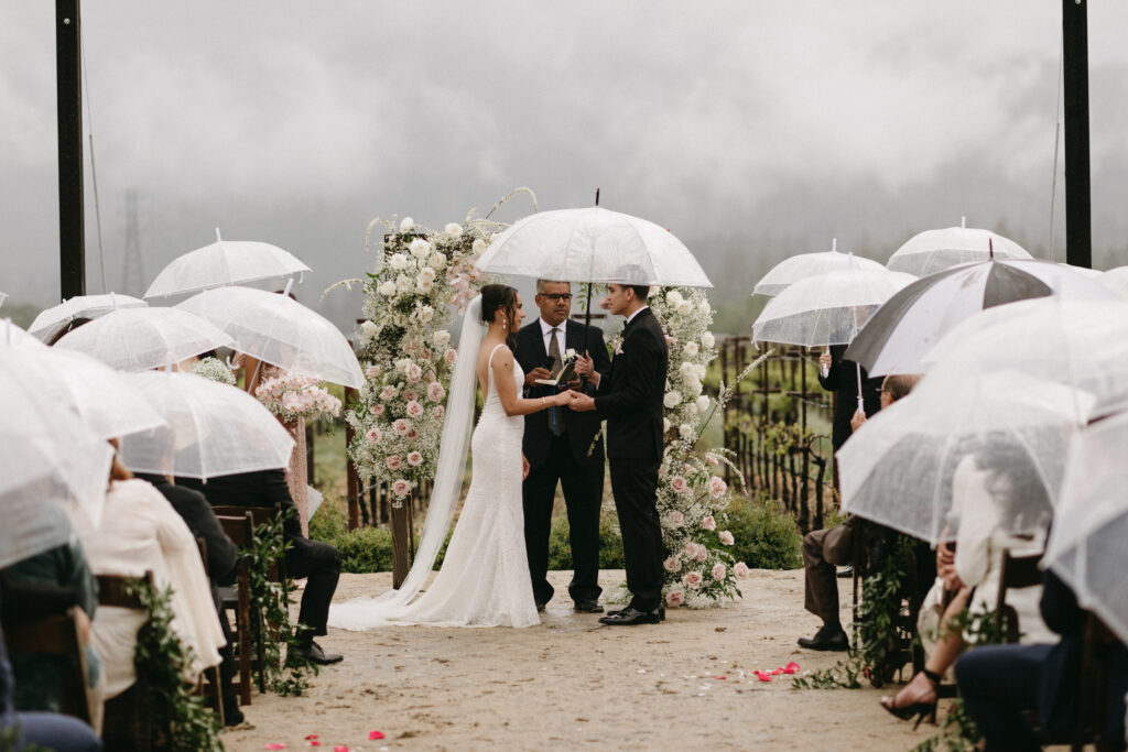Couple standing at the altar in the rain. wedding was planned by Talia Eliana Events/Terra Coast Events