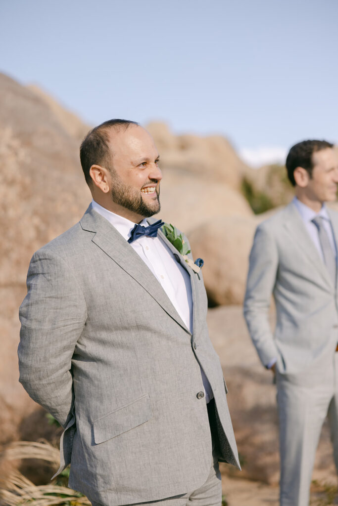 Groom standing at the end of the aisle during ceremony in Joshua Tree